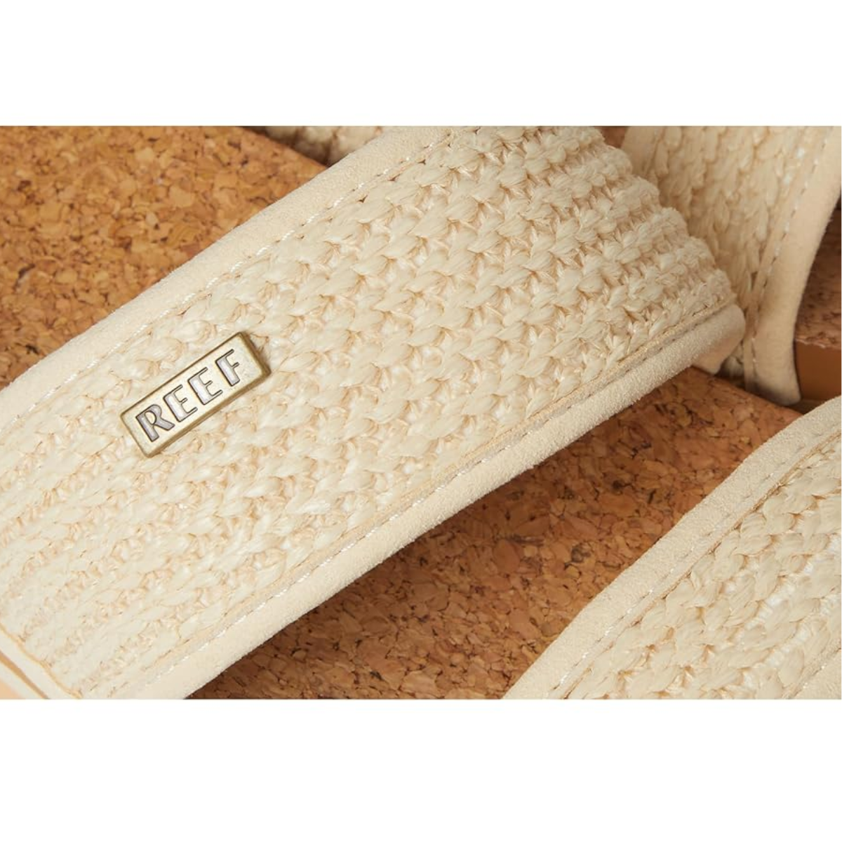 Close-up of the Reef Cushion Vista Hi in Vintage Raffia by REEF, featuring woven beige straps, a cushioned cork footbed with arch support, and a small metal REEF tag attached to one strap.