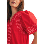 A woman wearing the FASHION GO Short Puff Sleeves Embroidered Shift dress in red, featuring pink decorative stitching along the neckline and sleeves, shown from the shoulders up.