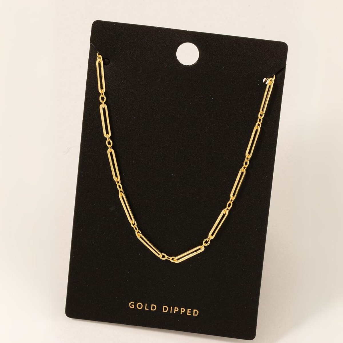 A Gold Dipped Dainty Oval Chain Necklace in Gold displayed on a black card with a hole at the top. The card proudly features "FASHION GO" written at the bottom.
