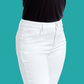 Model wears FASHION GO 30" inseam Better Butter White Jeans with a black top, shown from mid-torso to upper thighs against a solid teal background.