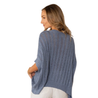 A woman with light brown hair, wearing white pants and the Sew In Love Relaxed Fit Dolman Sleeves Open Knit Top in blue, stands facing away to show the back of the vertical-striped sweater.