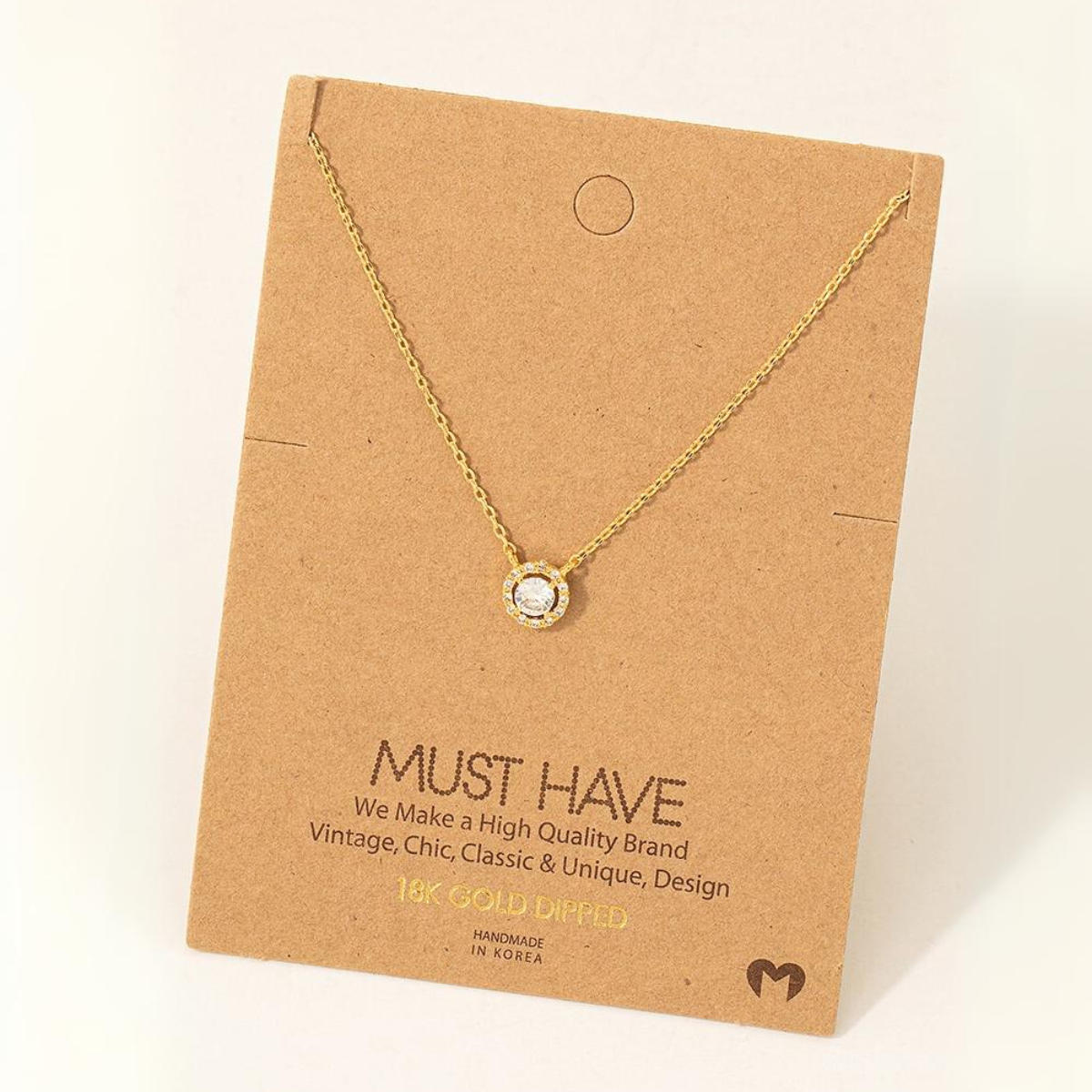 A Gold Dipped Cubic Zirconia Halo Pendant Necklace, displayed on a brown card that reads "MUST HAVE." The card mentions it is a high-quality, handmade product from Korea by FASHION GO.