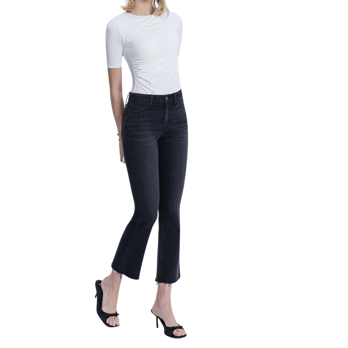 A person wearing a fitted white short-sleeve top, FASHION GO High Rise Raw Hem Ankle Bootcut Jeans - Black, and black open-toe heels stands against a white background.