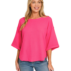 A woman wearing the Zenana Double Knit Exposed Seam Curved Hem Top in bright pink and blue jeans stands against a white background.