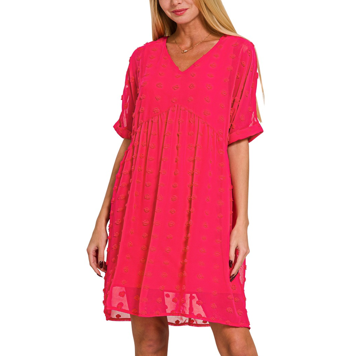 A woman wearing a loose-fitting, bright pink Swiss Dot Baby Doll Dress by FASHION GO with a V-neck and short sleeves.