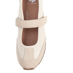 The Alina MaryJane Sneaker by Yellow Box is shown from above on a white background, featuring a cream colorway with a beige suede strap and toe cap that blends classic style with cushioned comfort.