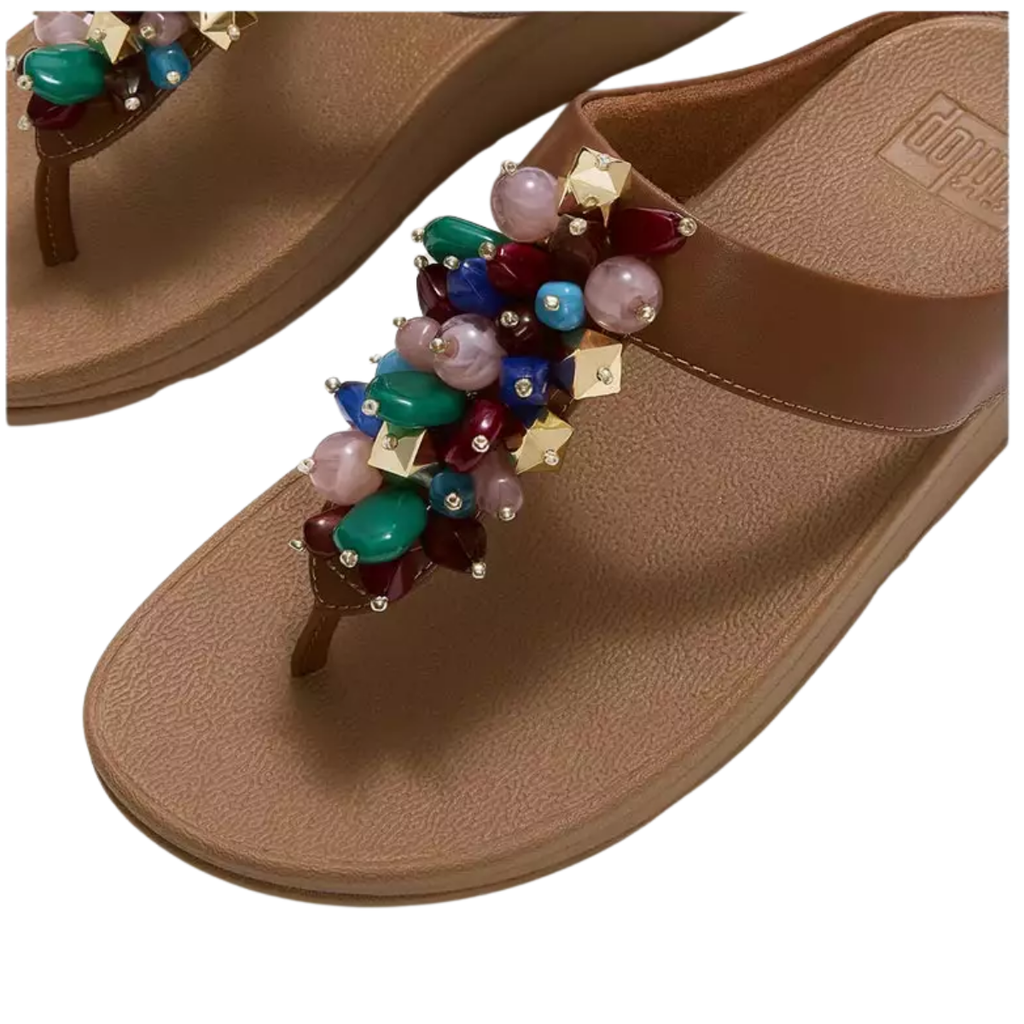 The Fino Bead Toe-Post Sandal by Fit Flop in Terracotta features a textured sole, a decorative cluster of multicolored beads with gold accents on the strap, and Microwobbleboard midsoles for enhanced comfort. Brand: FITFLOP USA LLC.