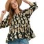 A woman wearing the Umgee Mix Floral Smocked Yoke Ruffle Sleeve Blouse and a tan hat with blue jeans poses, her hand adjusting the brim of her hat.