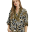 A woman wears the Umgee Abstract Print Midi Dress, featuring a flowy silhouette, abstract black, white, and olive green designs, and a V-neckline with decorative trim.