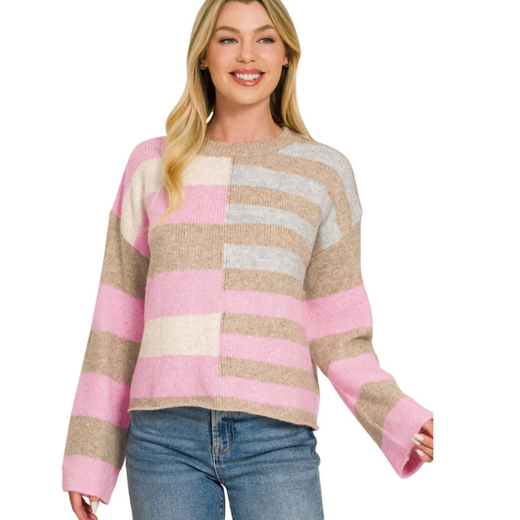 A woman stands smiling against a white background, wearing the FASHION GO Lightweight Wool Blend Color Block Sweater featuring long sleeves and pink, beige, and white stripes, paired with blue jeans—a great choice to refresh your fall wardrobe.
