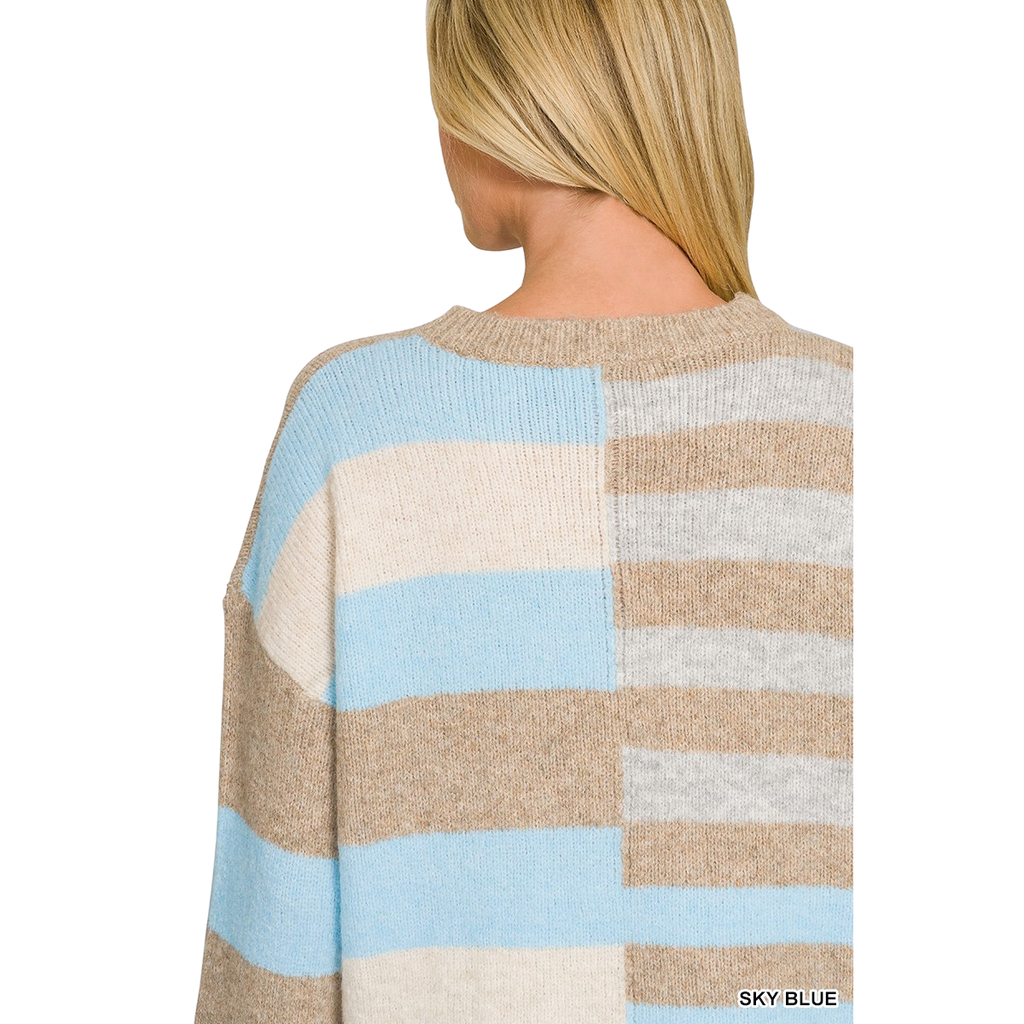 A person with straight blonde hair is shown from the back against a white background, wearing the FASHION GO Lightweight Wool Blend Color Block Sweater. This sweater features wide horizontal stripes in beige, blue, white, and gray tones. Its lightweight wool blend makes it a perfect addition to any fall wardrobe.