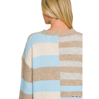 A person with straight blonde hair is shown from the back against a white background, wearing the FASHION GO Lightweight Wool Blend Color Block Sweater. This sweater features wide horizontal stripes in beige, blue, white, and gray tones. Its lightweight wool blend makes it a perfect addition to any fall wardrobe.
