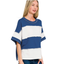 A woman is wearing the Zenana French Terry Color Block Top, a loose-fitting blue and white striped design with raw edge details, standing against a white background.