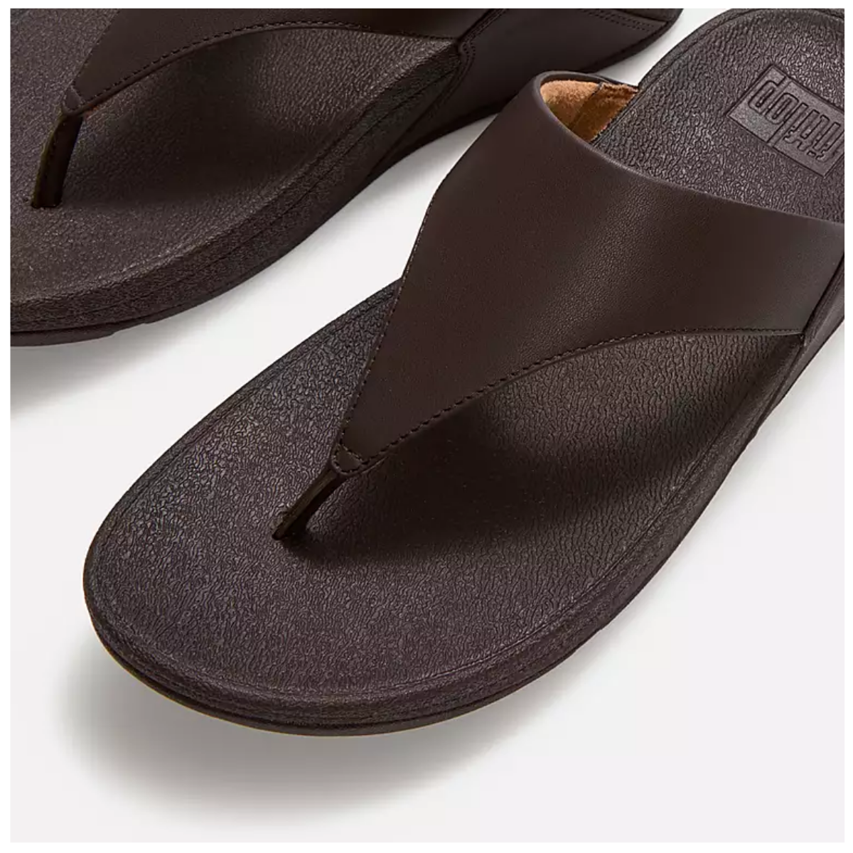A close-up of the Lulu Leather Toe Post in Chocolate Brown by FITFLOP USA LLC, a dark brown leather sandal with a Microwobbleboard midsole, shown on a white background. Main image