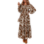 A woman wearing the FASHION GO Floral Smocked Bodice Frill Tiered Dress—a long, brown and white bohemian floral print dress with long sleeves—paired with a shoulder bag and brown ankle boots.
