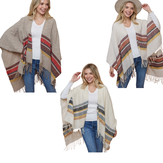 A woman models three FASHION GO Striped Wraps in beige, cream, and off-white, each with chic multi-stripe patterns and fringed edges, styled effortlessly over a white top with jeans.