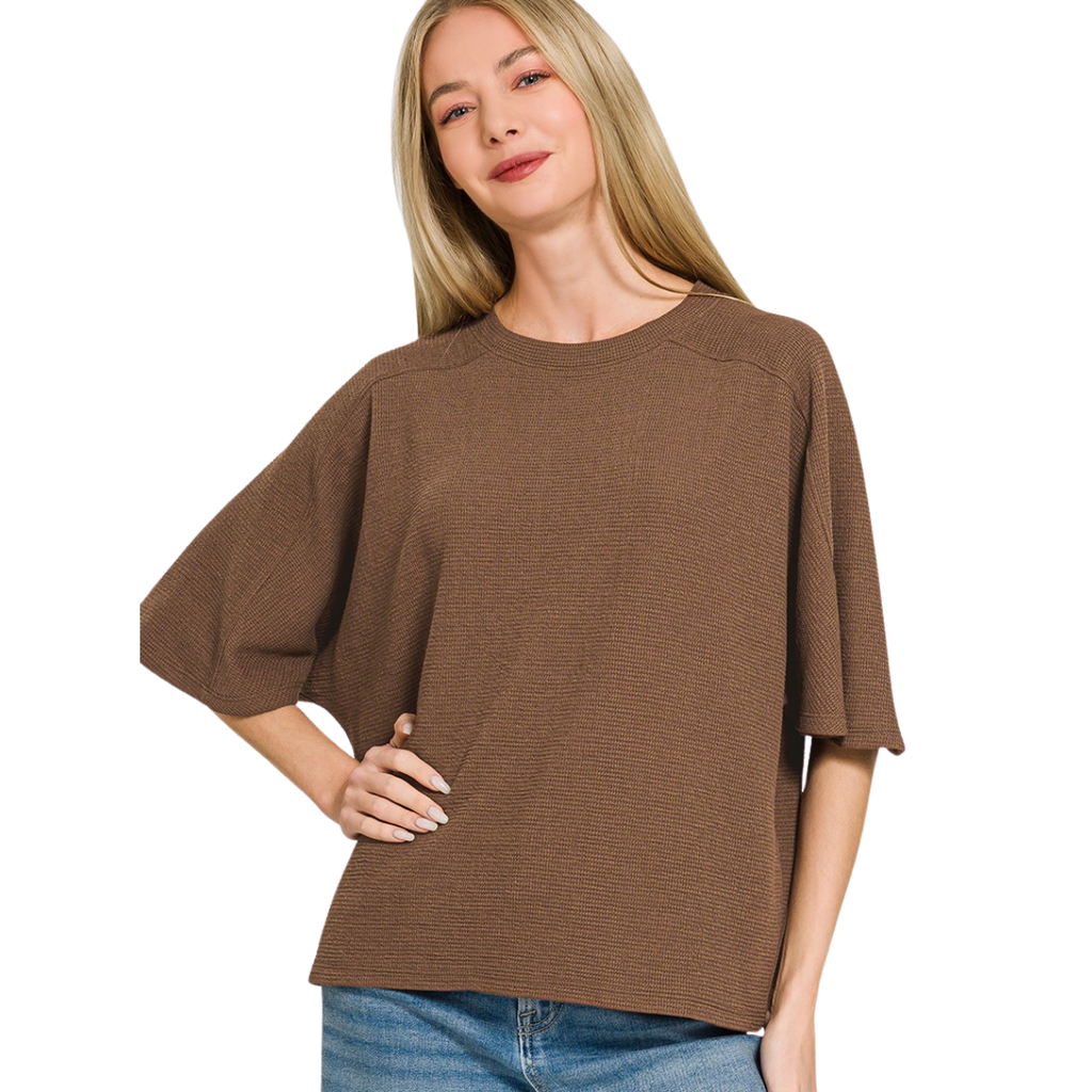 A woman with long blonde hair models the Zenana Double Knit Short Sleeve Top, paired with blue jeans, standing with one hand on her hip against a white background.