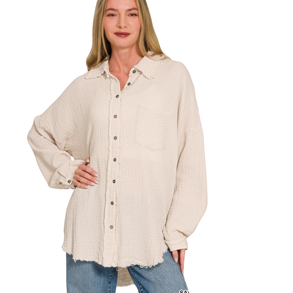A woman wears the Zenana Gauze Button Down Top in beige, featuring a relaxed fit and front pocket, paired with blue jeans against a white background.