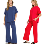 Two women wear the Zenana Scuba Curved Hem Top & Pants Set—one in blue, one in red—with loose-fit pants and curved hem tops, finishing their relaxed look with sandals.