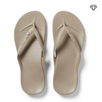 The Archies Arch Support Flip Flops Crystal Taupe by ARCHIES FOOTWEAR LLC are shown from above, featuring beige color, textured soles, arch support, and a small crystal detail on each strap against a white background.