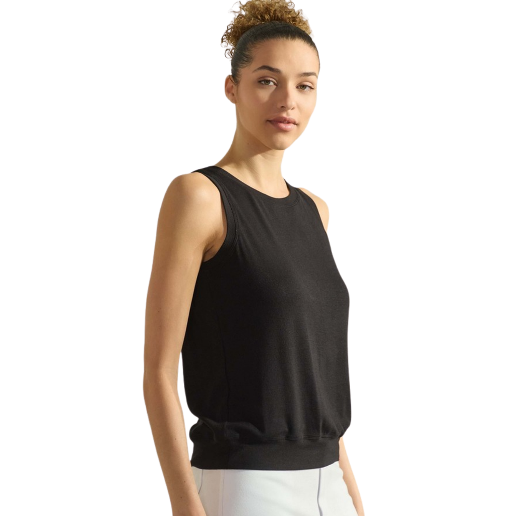 A woman stands facing forward against a plain white background wearing the FASHION GO Women's Ribbed Viscose Crew Neck Tank in black with white pants.