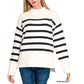A woman wears the FASHION GO Striped Mock Neck Sweater in ivory with black stripes, ribbed cuffs and hi-low hem, paired with blue jeans.