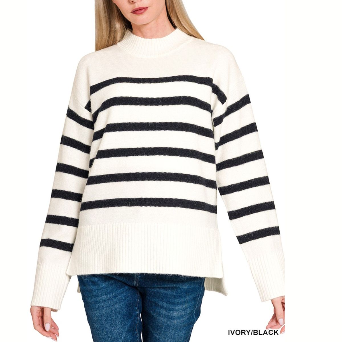 A woman wears the FASHION GO Striped Mock Neck Sweater in ivory with black stripes, ribbed cuffs and hi-low hem, paired with blue jeans.