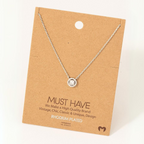 A Gold Dipped Cubic Zirconia Halo Pendant Necklace from FASHION GO is displayed on a brown cardboard backing labeled "MUST HAVE." The card mentions qualities like vintage, chic, classic, and unique design.