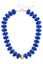 Make a bold impression with the Canvas Style San Sebastián Beaded Resin Necklace, featuring large round blue resin beads, a central gold bead, metal spacers, and an adjustable gold chain clasp.