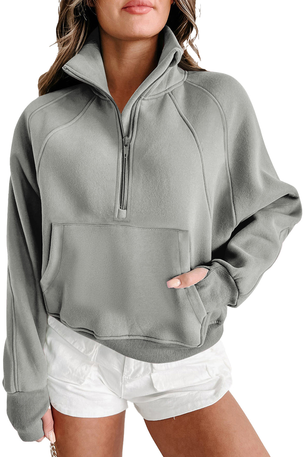 A woman with long, wavy hair stands sideways wearing a high-quality Shewin Gray Zip Up Stand Collar Ribbed Thumbhole Sleeve Sweatshirt and white shorts.