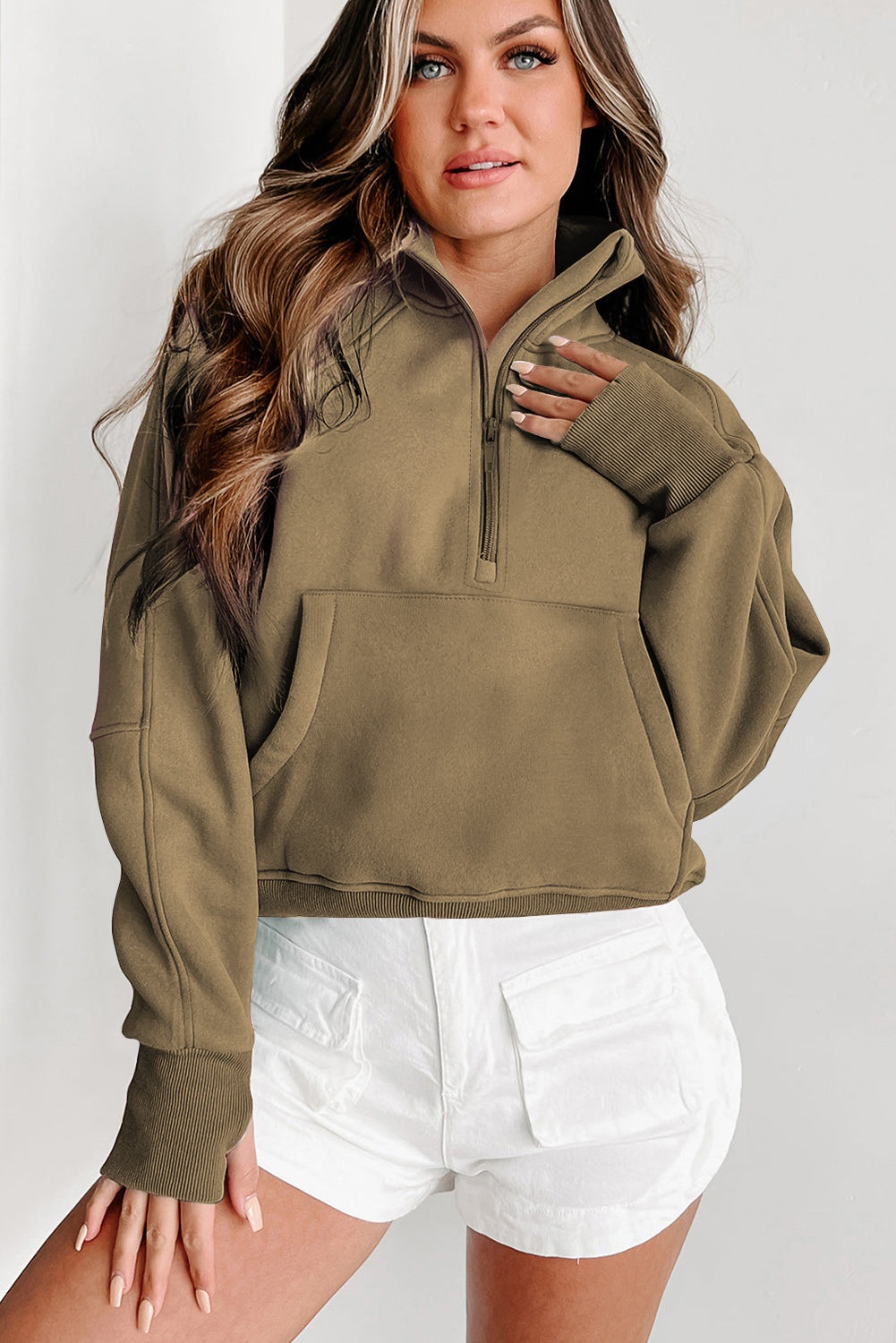 A woman with long wavy hair wears a Shewin gray zip-up stand collar ribbed thumbhole sleeve sweatshirt made of high-quality material and white shorts.