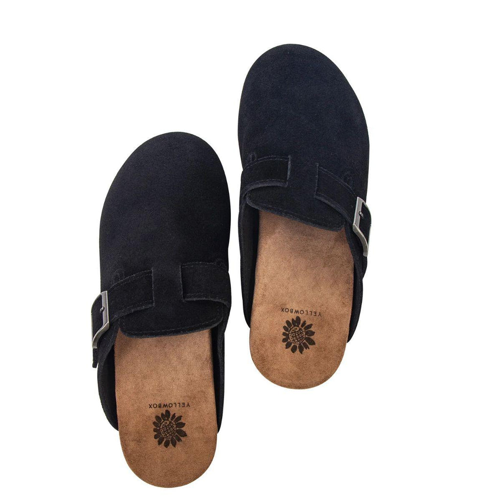 The Mulani Ladies Suede Clog by YELLOW BOX - CIT is displayed on a white background—an effortlessly stylish everyday shoe in black suede, featuring buckle accents and tan insoles adorned with a sunflower logo.