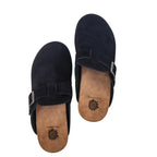 The Mulani Ladies Suede Clog by YELLOW BOX - CIT is displayed on a white background—an effortlessly stylish everyday shoe in black suede, featuring buckle accents and tan insoles adorned with a sunflower logo.