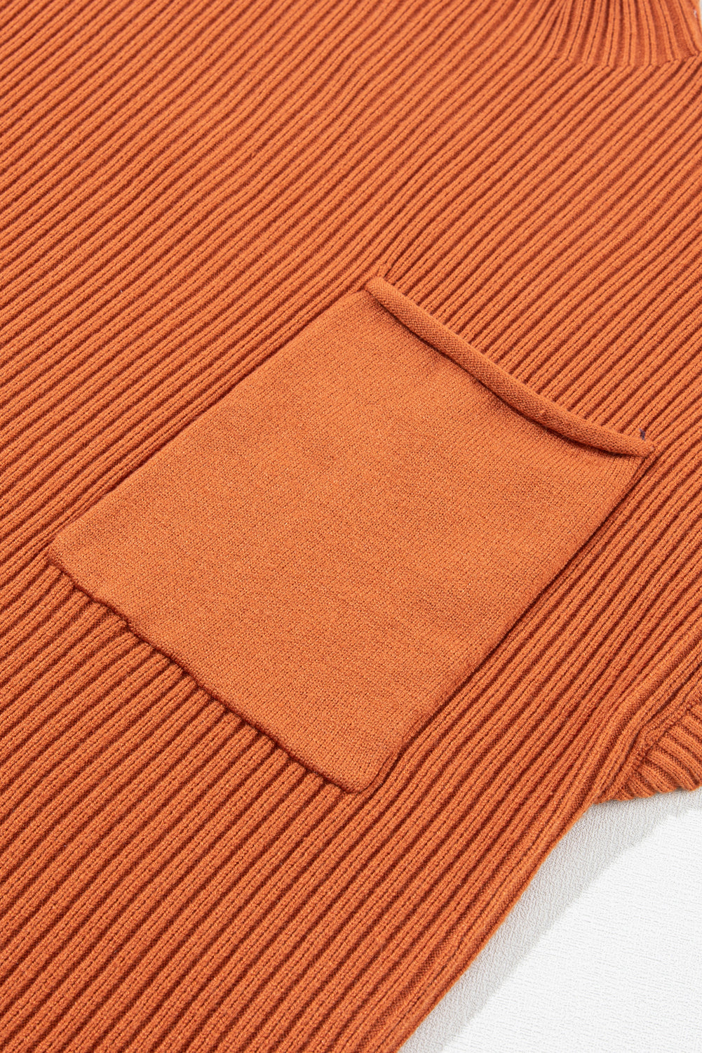 Close-up of the Shewin Patch Pocket Ribbed Knit Short Sleeve Sweater in orange, made from versatile ribbed fabric with a rectangular side pocket. Ideal for transitional weather.