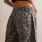 A person is seen from the back wearing Dipped Shop’s Leopard Print Loose Midi Waist Wide Leg Jeans in brown and black micro stretch denim.