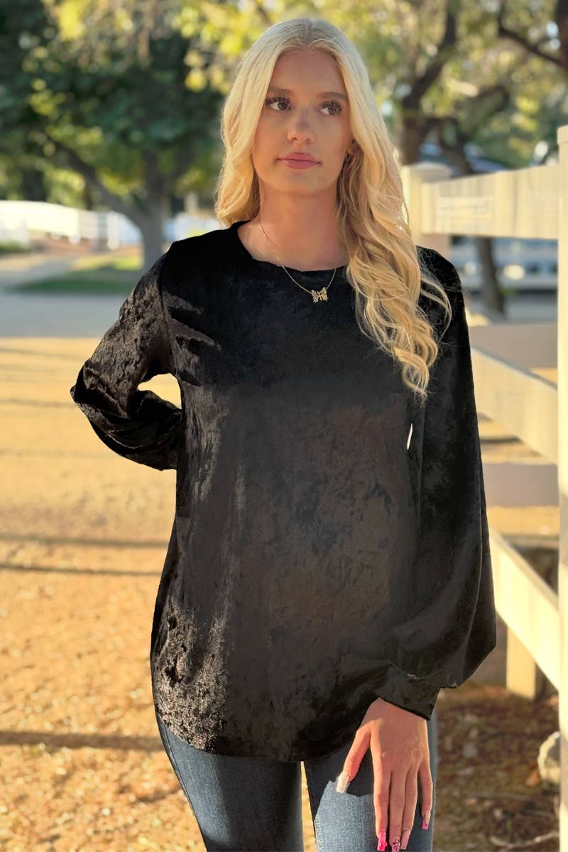 A woman with long blonde hair stands outdoors, wearing the 24-Hrs Fashion Crushed Velvet Top and blue jeans, with one hand resting on a wooden fence.
