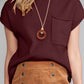 Dressed in a Shewin Patch Pocket Ribbed Knit Short Sleeve Sweater, perfect for transitional weather, the person pairs it with a brown skirt featuring buttons, while a necklace with a circular pendant elegantly hangs around their neck.