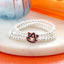 The Auburn Glitter Enamel Logo Stretch Bracelet Set by Seasons Jewelry showcases an officially licensed silver beaded design with the Auburn University logo charm accented in glitter enamel, displayed on a white round surface beside a blue glass object and orange background elements.