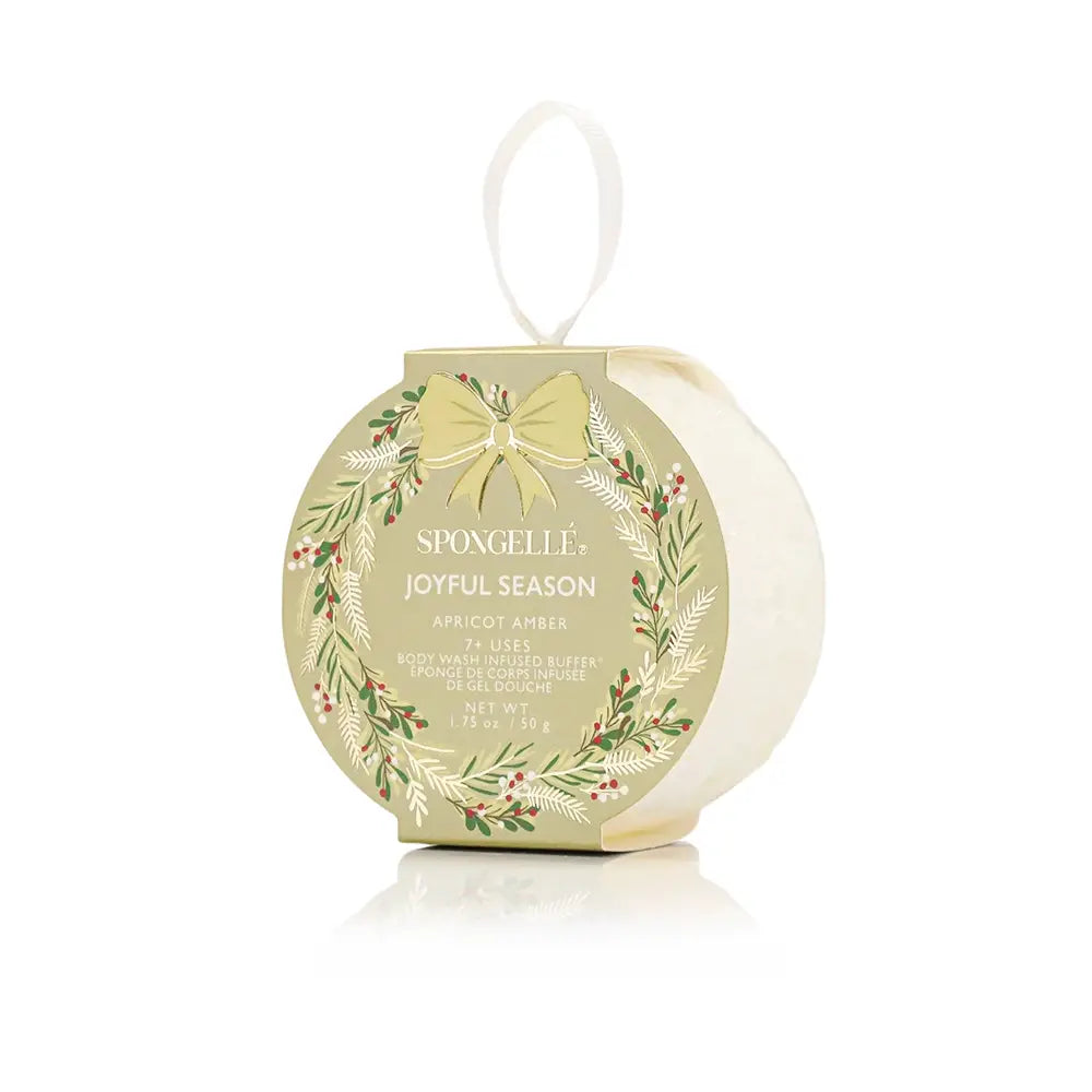 Round, holiday ornament-style Spongelle Holiday Bath Soap Sponges buffer in gold packaging with a ribbon loop for hanging.