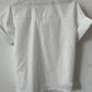 The White Relaxed Short Sleeve Blouse by Rosa Clothing exudes chic style, shown from the back on a hanger against a plain white wall for a classic look.