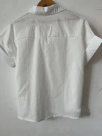 White Relaxed Fit Short Sleeve Blouse by FASHION GO shown from the back, hanging on a wooden hanger against a plain white wall—a perfect casual top for everyday comfort.