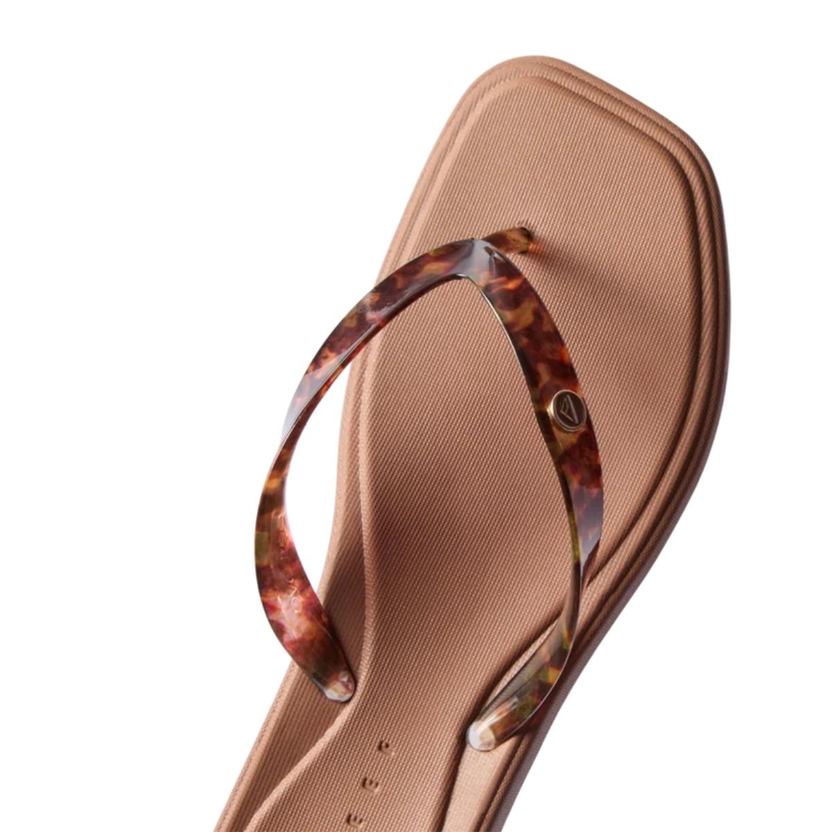 A close-up of a single beige, square-toed Solaye Flip Flop in Tortoise by REEF, featuring brown marbled tortoise print straps and photographed on a white background—an elegant, versatile update to classic women’s flip-flops.