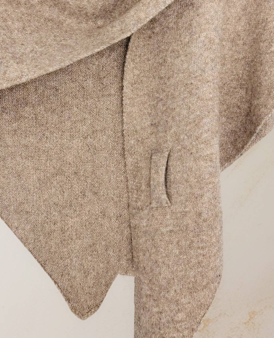 A close-up of a beige wool coat with welt pocket and pointed hem, styled with the JC Sunny Fashion Cashmere-Blend Knit Triangle Shawl featuring a cross-front design, set against a neutral background.