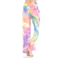 A person is standing barefoot against a white background, wearing Leggings Depot Buttery Soft Print Pajama Pants featuring a loose fit, high waist, elastic waistband, and pink, yellow, blue, and green tie dye print.