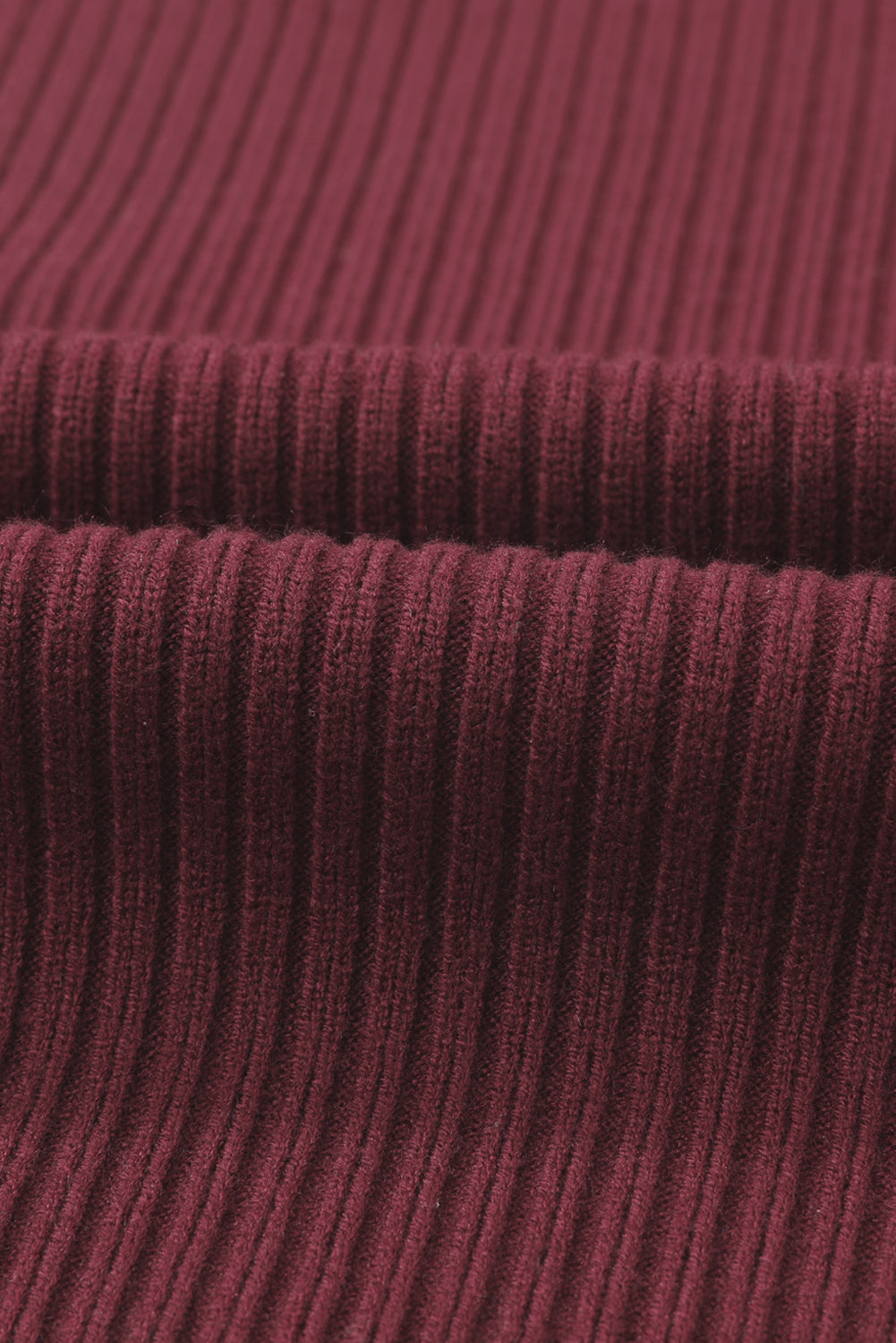 Close-up of ribbed, dark red fabric folded over itself from Shewin's Patch Pocket Ribbed Knit Short Sleeve Sweater, evoking coziness.