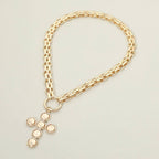 Sensibling Corp.’s Pearl Cross Charm Pendant Chunky Chain Statement Necklace, featuring a gold chunky chain and a textured cross pendant adorned with six round, light-colored pearl-like stones, is showcased against a plain, neutral background.