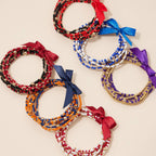 Five stacked sets of colorful Game Day Seed Beaded Bracelet sets, each tied with a small satin ribbon bow.