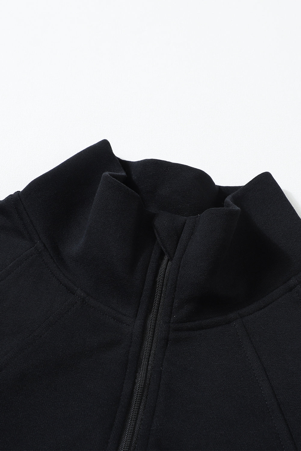 Close-up image of the Gray Zip Up Stand Collar Ribbed Thumbhole Sleeve Sweatshirt from Shewin showcases its texture and folds in a spiral pattern, adding a modern touch.