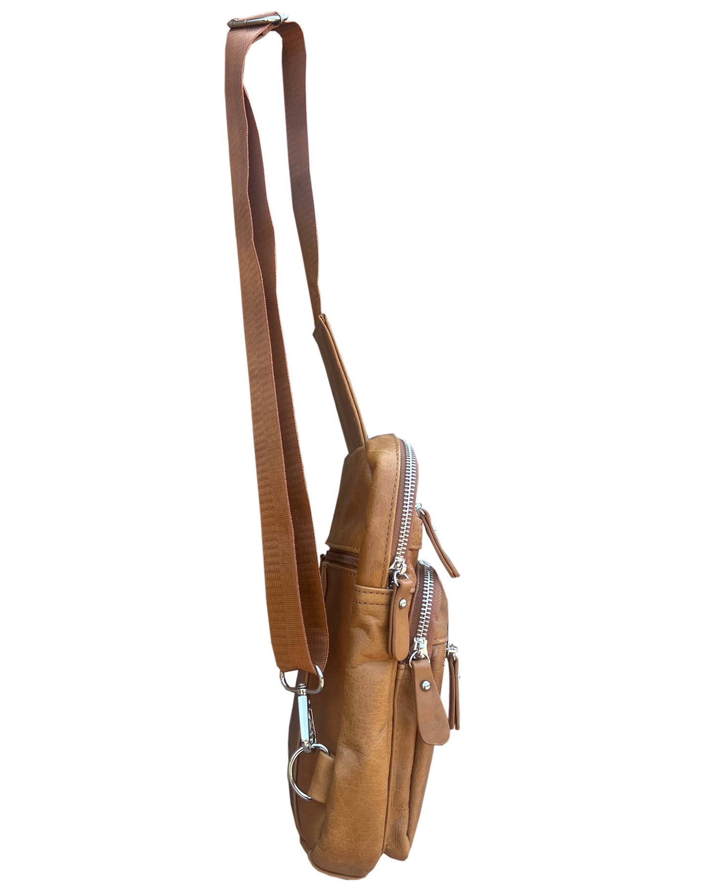 Side view of the Roma Leathers, Inc. Cowhide leather sling bag backpack with adjustable strap, two zippered compartments, and silver-tone hardware against a white background.