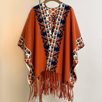 The ACCITY Vintage Plaid Tassel Shawl Women Winter Cape features a rust hue, blue and white geometric V-shaped patterns, and fringe at the hem—displayed on a hanger against a plain background, it's your cozy winter essential.